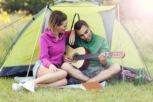 Couple camping and playing guitar