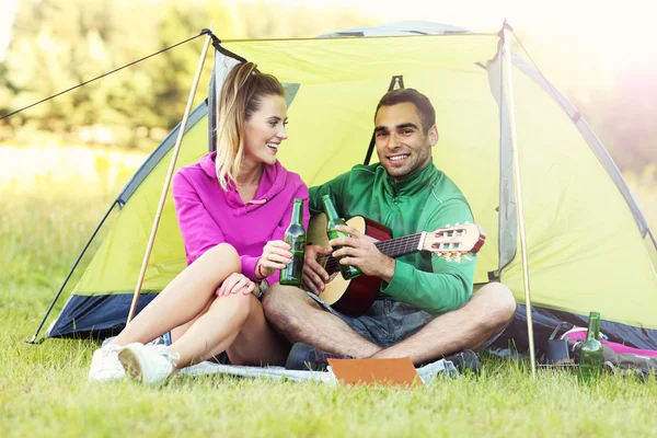 Couple camping and playing guitar