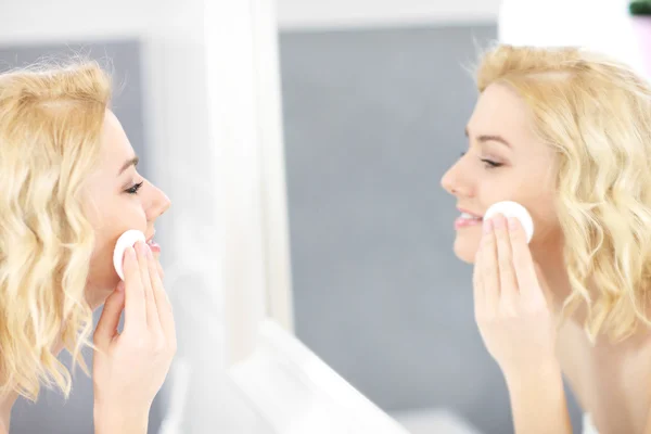 Happy woman cleaning face