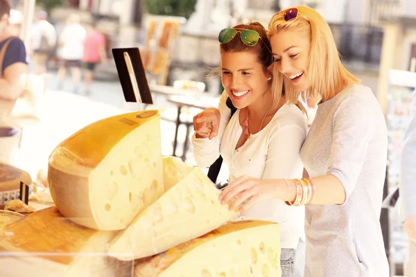 Women shopping for cheese on food market