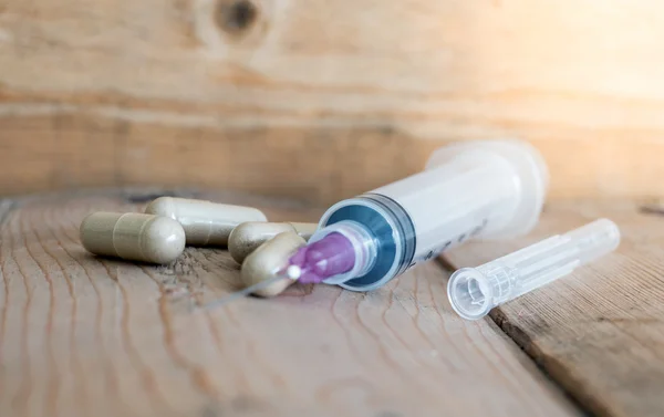 Injection needle and herb capsule,injection needle on the wooden table,Selected Focus