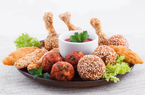 Various fried chicken appetizers with tomato dip