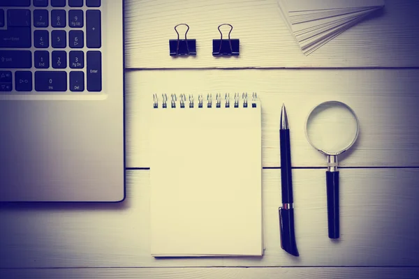 Office desk table with supplies. Top view. Copy space for text. Laptop, blank notepad, pen and magnifying glass