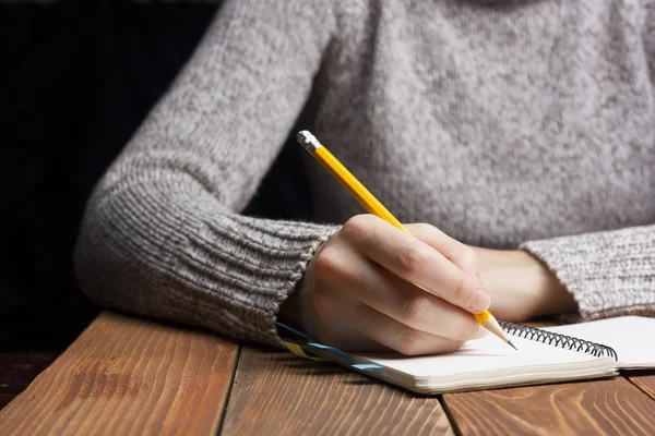 Female hands with pencil writing on notebook