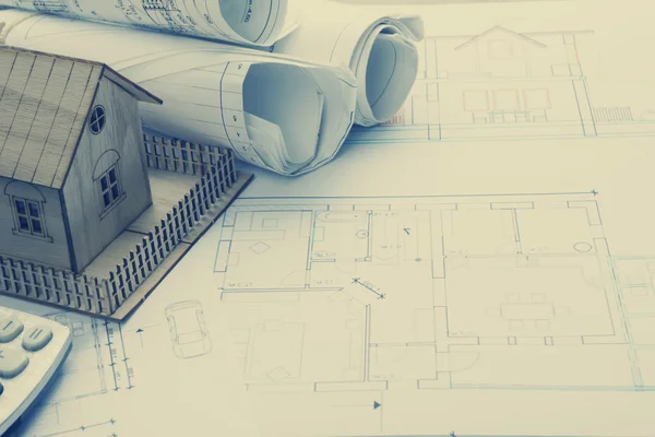 Real Estate concept. Architect workplace. Architectural project, blueprints, blueprint rolls and model house on plans. Top view. Construction background. Engineering tools.