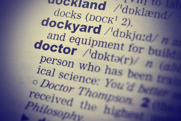 Close-up of word in English dictionary. Doctor definition and transcription.