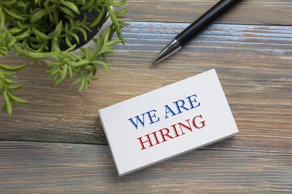 We are Hiring. Office desk table with business card, pen and flower. Top view.