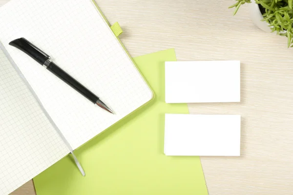 Business card blank, notepad, flower and pen at office desk table top view. Corporate stationery branding mock-up