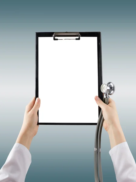 Female doctor's hand holding blank medical clipboard and stethoscope on blurred background. Concept of Healthcare And Medicine. Copy space.