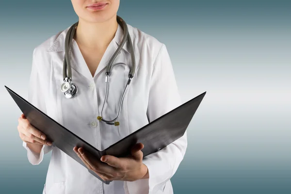 Female doctor's hand holding stethoscope and clipboard on blurred background. Concept of Healthcare And Medicine. Copy space.