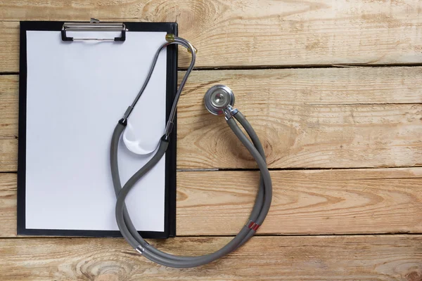 Stethoscope and clipboard on wood table top view . Medical background. Concept for diet, healthcare, nutrition or medical insurance