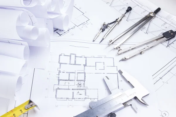 Architectural project, blueprints, blueprint rolls and divider compass, calipers on plans Engineering tools view from the top. Copy space. Construction background.