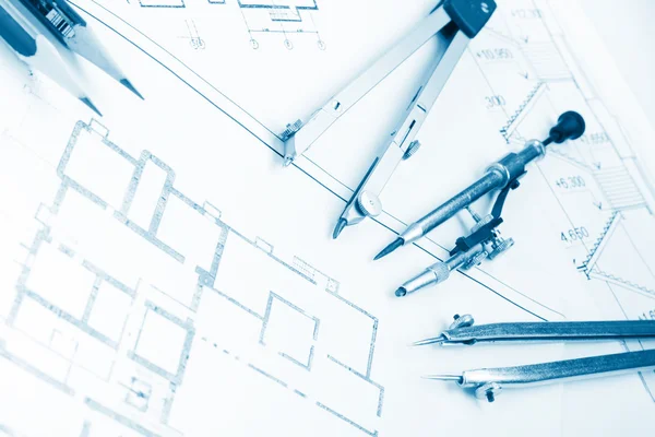 Architectural project, blueprints, blueprint rolls and divider compass, calipers, folding ruler on plans Engineering tools view from the top. Copy space. Construction background. Blue toned