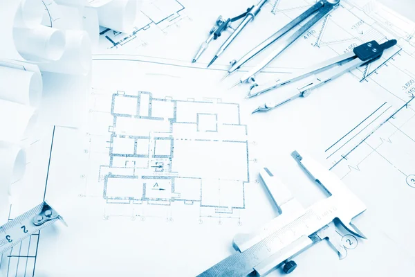 Architectural project, blueprints, blueprint rolls and divider compass, calipers, folding ruler on plans Engineering tools view from the top. Copy space. Construction background. Blue toned