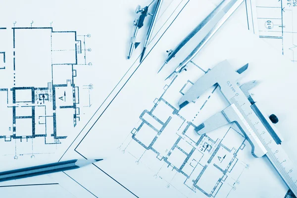 Architectural project, blueprints, blueprint rolls and divider compass, calipers, folding ruler on plans Engineering tools view from the top. Copy space. Construction background. Blue toned