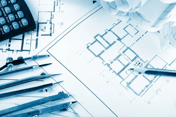 Architectural project, blueprints, blueprint rolls and divider compass, calipers, folding ruler on plans Engineering tools view from the top. Copy space. Construction background. Blue toned