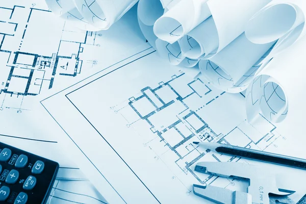 Architectural project, blueprints, blueprint rolls and divider compass, calipers, folding ruler on plans Engineering tools view from the top. Copy space. Construction background. Blue toned