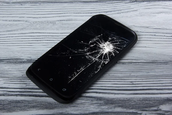 Modern broken mobile phone on white wooden background. Copy space. Top view
