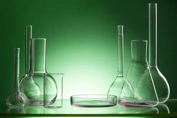 Assorted empty laboratory glassware, test-tubes. Green tone medical background. Copy space