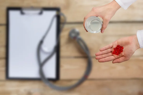 Healthcare and medicine concept - Female doctors hand holding medical pills on blurred background. First aid