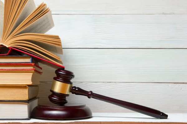 Law book with wooden judges gavel on table in a courtroom or law enforcement office.