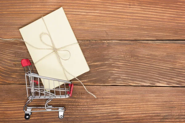 Online shopping concept - Empty Shopping Cart, laptop and tablet pc, gift box on rustic wooden background