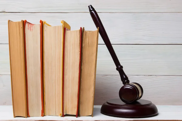 Law book with wooden judges gavel on table in a courtroom or law enforcement office.