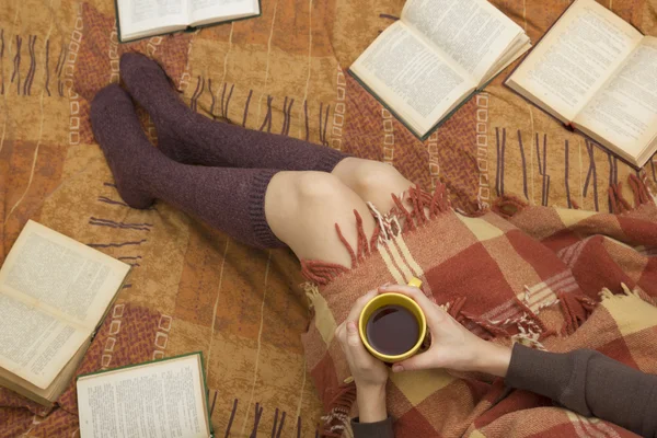 Woman on the bed with old book and cup of coffee in hands, top view point. Copy space for text. Soft photo