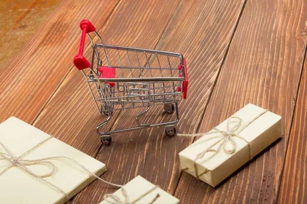Online shopping concept - Empty Shopping Cart, laptop and tablet pc, gift box on rustic wooden background