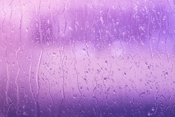 Rain on a window in purple colors