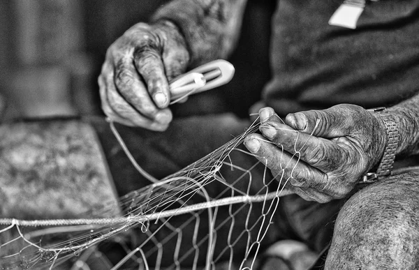 Old fisherman\'s village of Trani intent to mend fishing nets BW