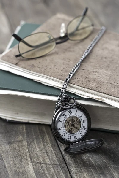 An antique pocket watch, glasses and books