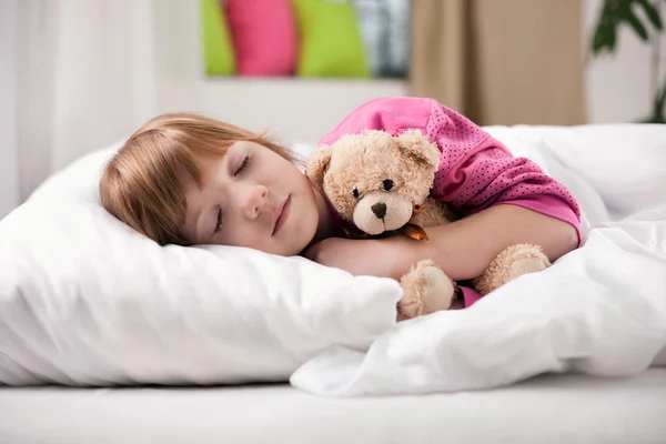 Adorable little girl sleeping in the bed with her toy