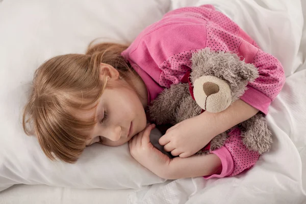 Adorable little girl sleeping in the bed with her toy