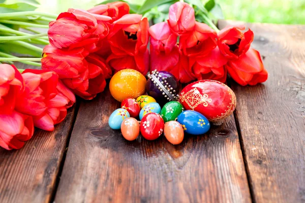 Easter background with easter eggs and red tulips.