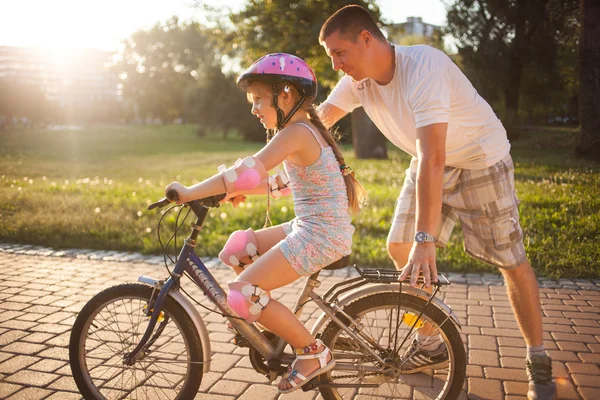 Girl learning to ride a bicycle with father in park