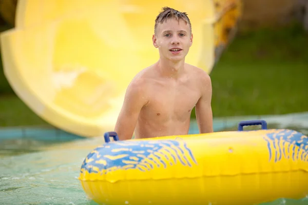 Funny excited child enjoying summer vacation in water park ridin