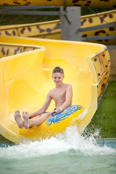 Funny excited child enjoying summer vacation in water park ridin