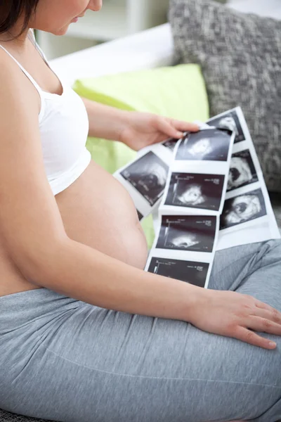 A shot of a pregnant woman looking her child's ultrasound pictu