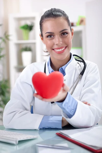 Friendly young female doctor holding a heart in his hands