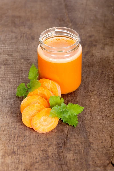 Organic carrot juice on wooden background
