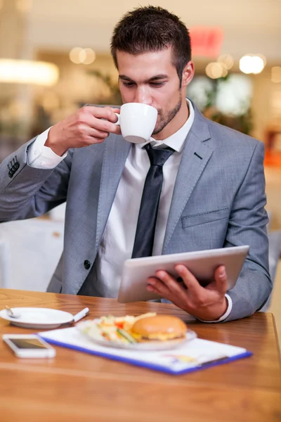 Businessman in the restaurant drinking coffee and working on dig