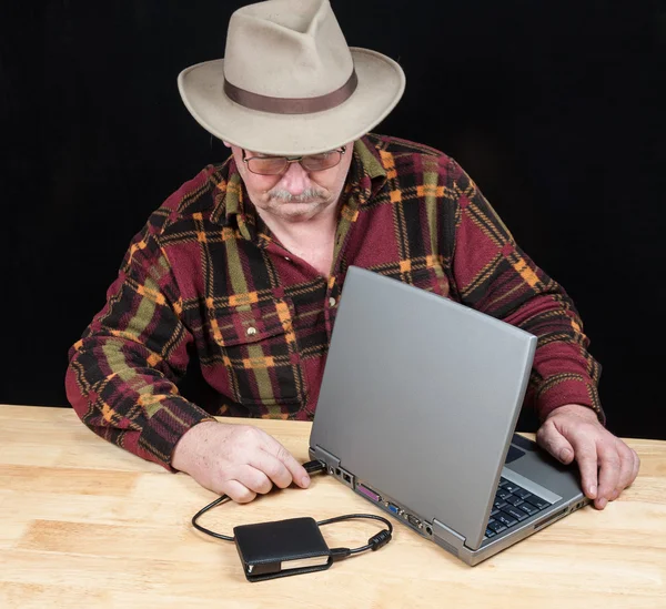 senior male with laptop and external hard drive