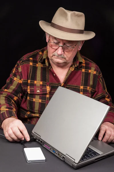 Senior male with laptop and external hard drive