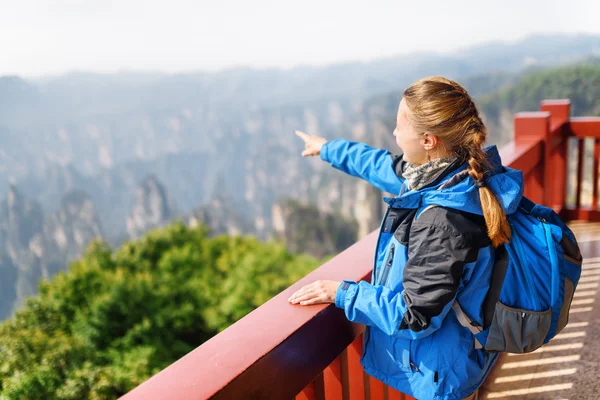 Young female tourist pointing at amazing mountains