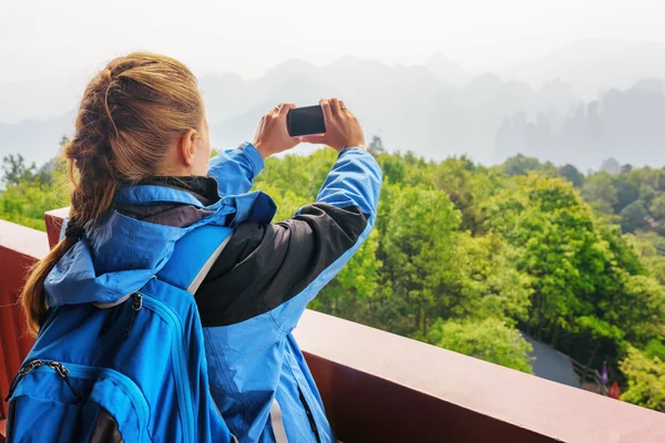 Closeup view of female tourist taking photo of mountains
