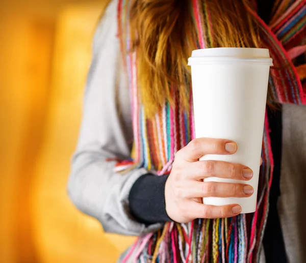 Young woman holding a tumbler of coffee in cafe