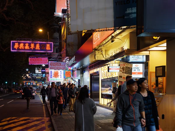 Pedestrians and illuminated signs on the street of night city Ho