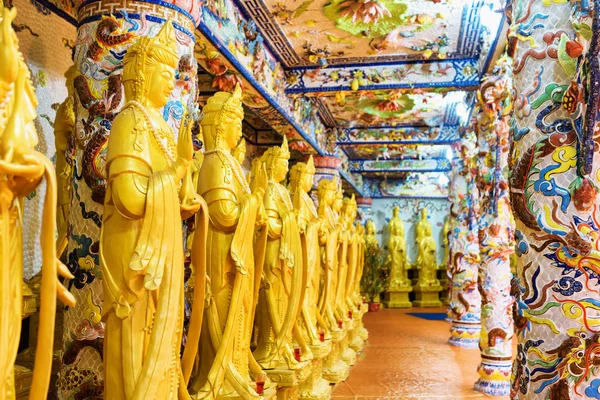 Golden Buddha statues along the wall in the interior of the Linh