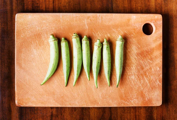 Green seed pods okra on a wooden board. Healthy popular food